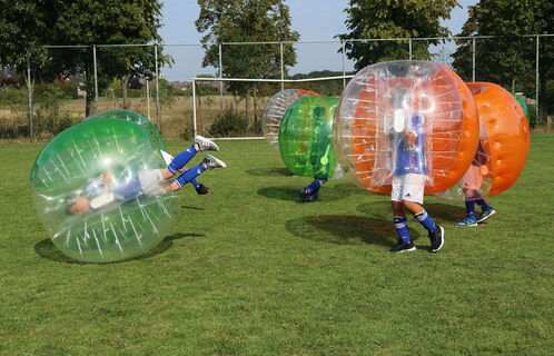 Kinder beim Fußballspielen in aufblasbaren Bubble-Bällen